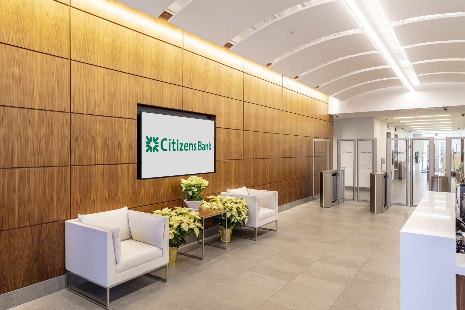 1 Modern bank lobby with wooden walls, a digital sign, seating area, and entrance turnstiles