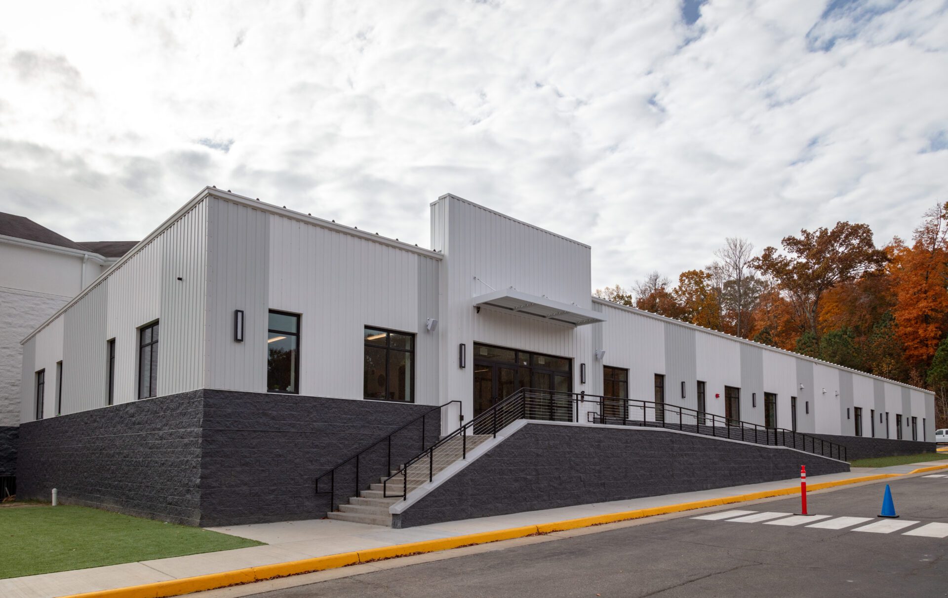 1 Aerial view of a modern suburban building with gray roofing and stone accents, surrounded by a parking lot