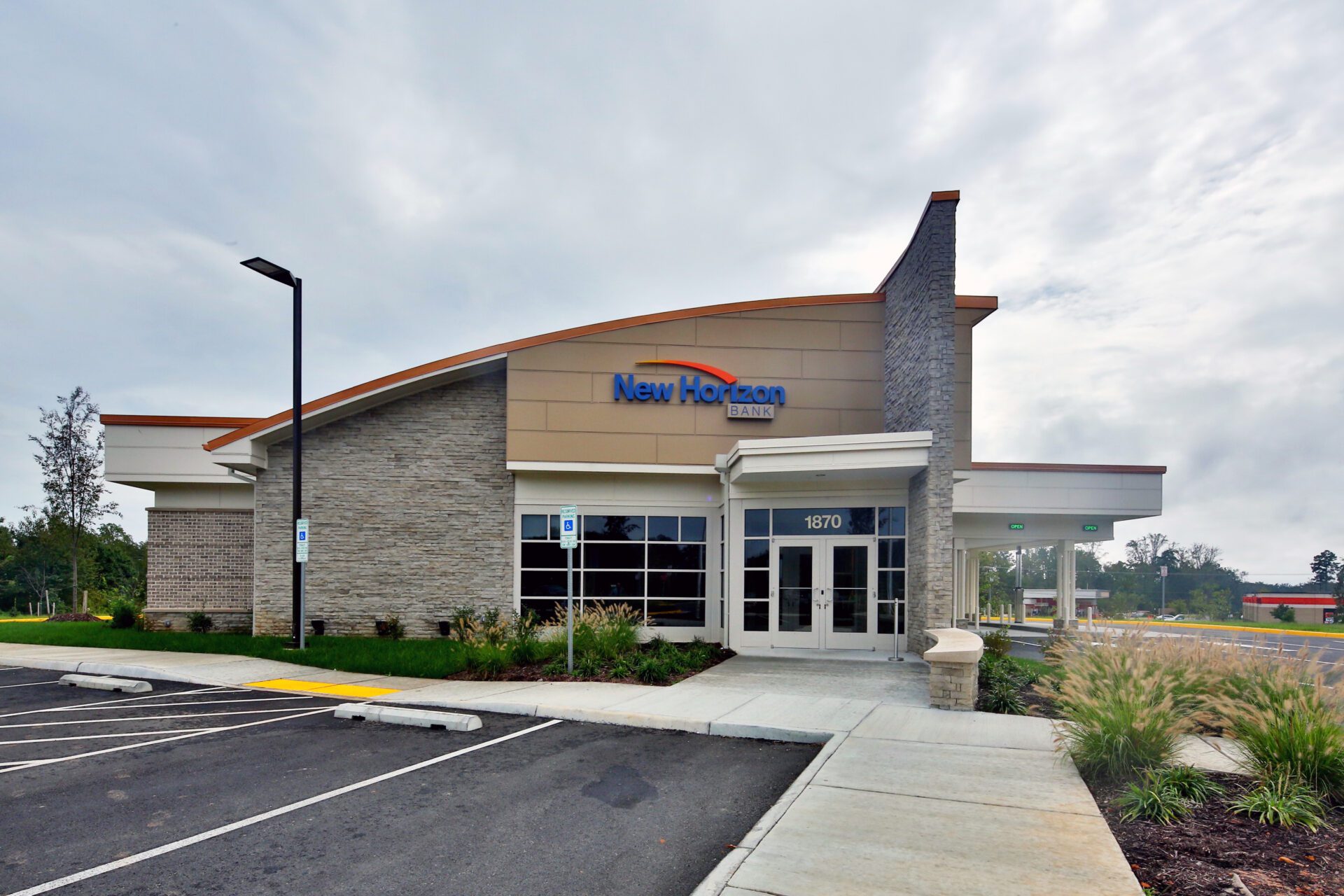6 Exterior of New Horizon Bank building with clear signage, parking lot in the foreground, and overcast sky